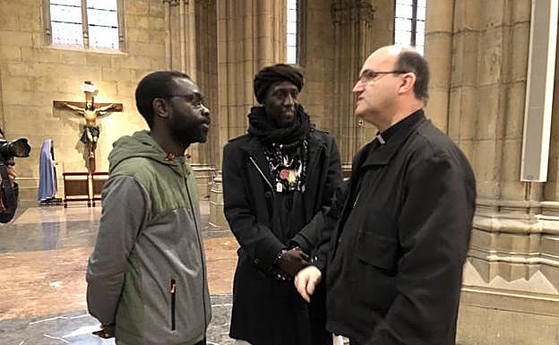 El obispo Munilla habla con dos inmigrantes antes de la presentación de la subida a Arantzazu. 