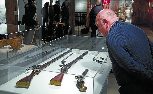 Un hombre contempla los fusiles y pistolas de chispa. 
