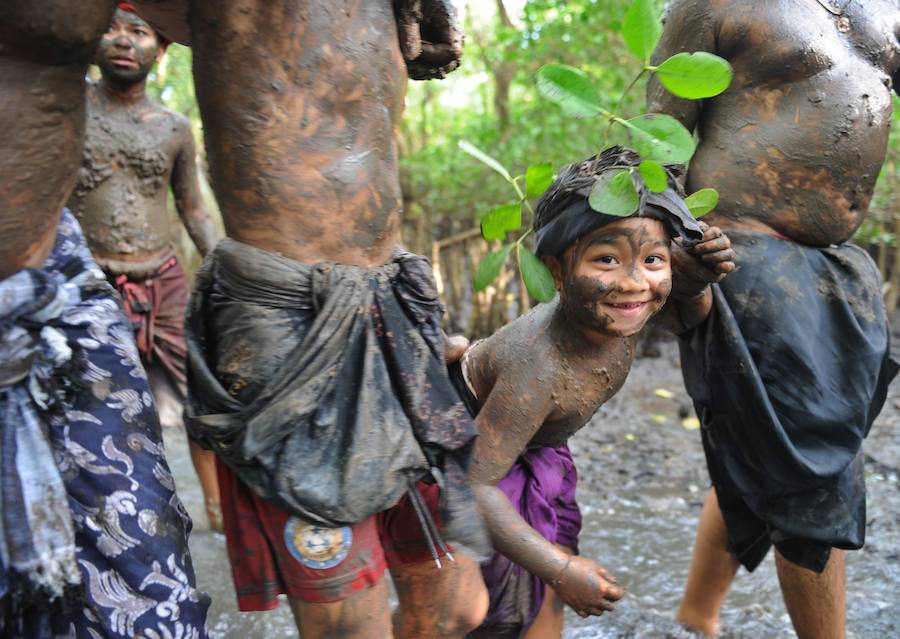 Niños y mayores se esparcen barro por todo su cuerpo durante el tradicional baño de barro conocido como Mebuug.buugan en la aldea de Kedonagn, cerca de Denpasar, en la isla balnearia indonesia de Bali.