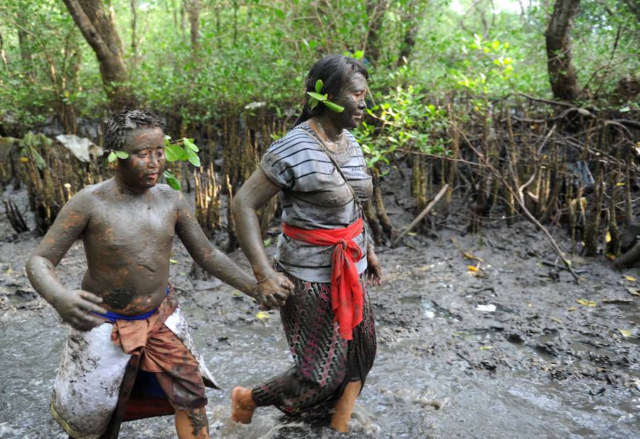 Niños y mayores se esparcen barro por todo su cuerpo durante el tradicional baño de barro conocido como Mebuug.buugan en la aldea de Kedonagn, cerca de Denpasar, en la isla balnearia indonesia de Bali.