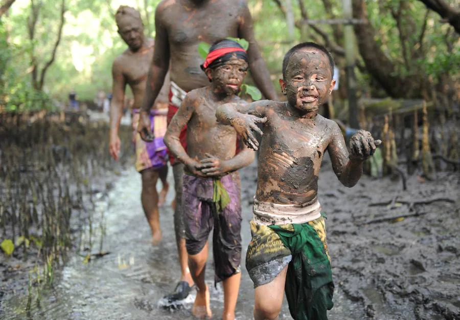 Niños y mayores se esparcen barro por todo su cuerpo durante el tradicional baño de barro conocido como Mebuug.buugan en la aldea de Kedonagn, cerca de Denpasar, en la isla balnearia indonesia de Bali.