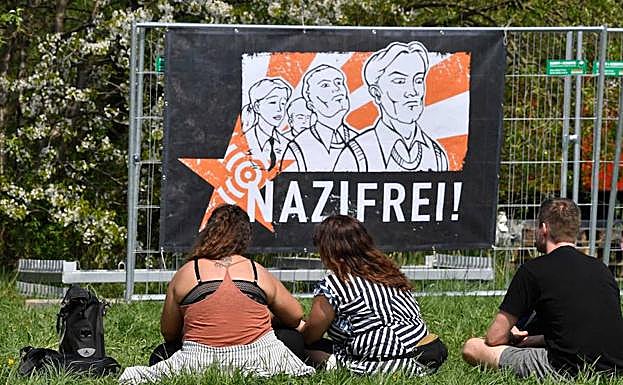 Asistentes a la contraprotesta frente a un cartel de 'Libre de nazis' justo al festival del cumpleaños de Hitler. 