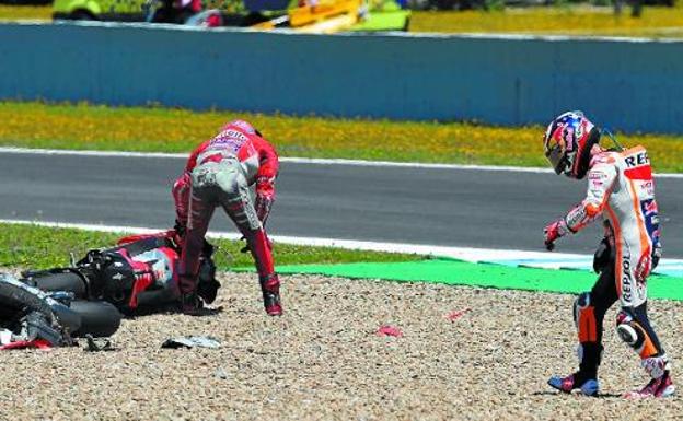 Accidente. Andrea Dovizioso y Jorge Lorenzo tratan de levantar las Ducati tras su accidente de Jerez, mientras el tercer implicado, Pedrosa, camina por la arena. 