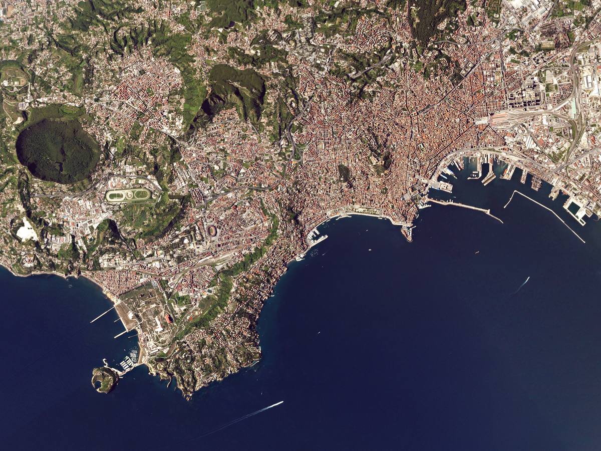 NÁPOLES (Italia). Los barcos pasan por la isla de Nisida (abajo a la izquierda) en su camino hacia el puerto histórico de Nápoles. La isla distintiva es la caldera hundida de un volcán que entró en erupción hace entre 8.000 y 10.000 años. Tiene un diámetro de 0,5 km y se eleva hasta 105 metros sobre las aguas del mar Tirreno. La histórica ciudad del Vesubio comenzó su historia en el s. VIII a. C. como la que se cree fue la primera colonia griega en occidente: Pitecusas, en la isla napolitana de Isquia.