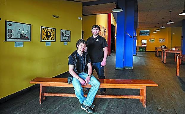 Joseba (eserita) eta Hur Astarbe beren sagardotegian, horman 'Sagarra-Manzana' bildumako koadro batzuk ikusten direla