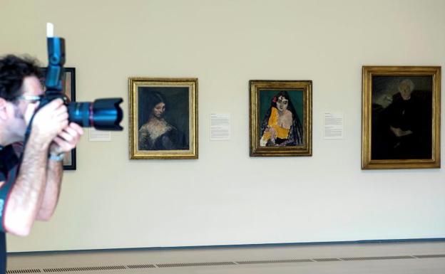 Un hombre fotografía las obras de Isidre Nonel (i), Henri Matisse (c) y Francisco Gutiérrez Cossío (d), que forman parte de la nueva sala del Centro Botín.