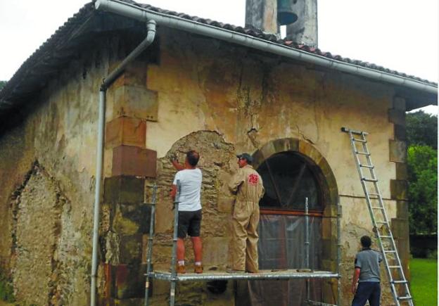 Miembros de la asociación 'Amigos de la ermita' el jueves picando la pared de la fachada principal. 