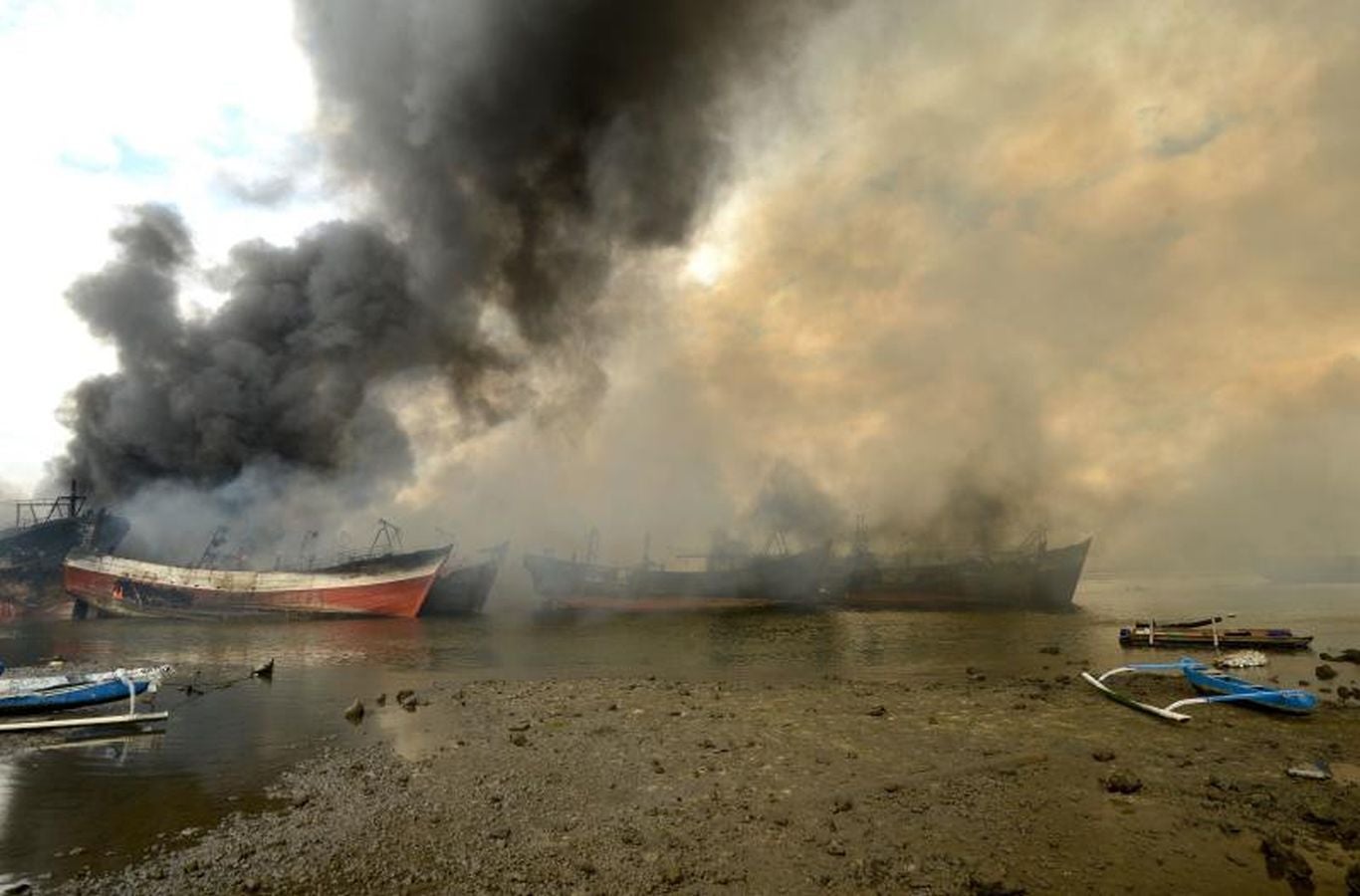 Varios bomberos trabajan en la extinción de un incendio de un barco en el puerto de Benoa, en Bali (Indonesia).