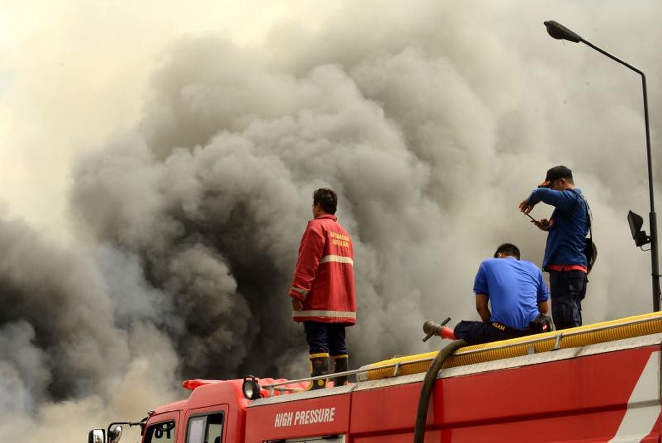 Varios bomberos trabajan en la extinción de un incendio de un barco en el puerto de Benoa, en Bali (Indonesia).