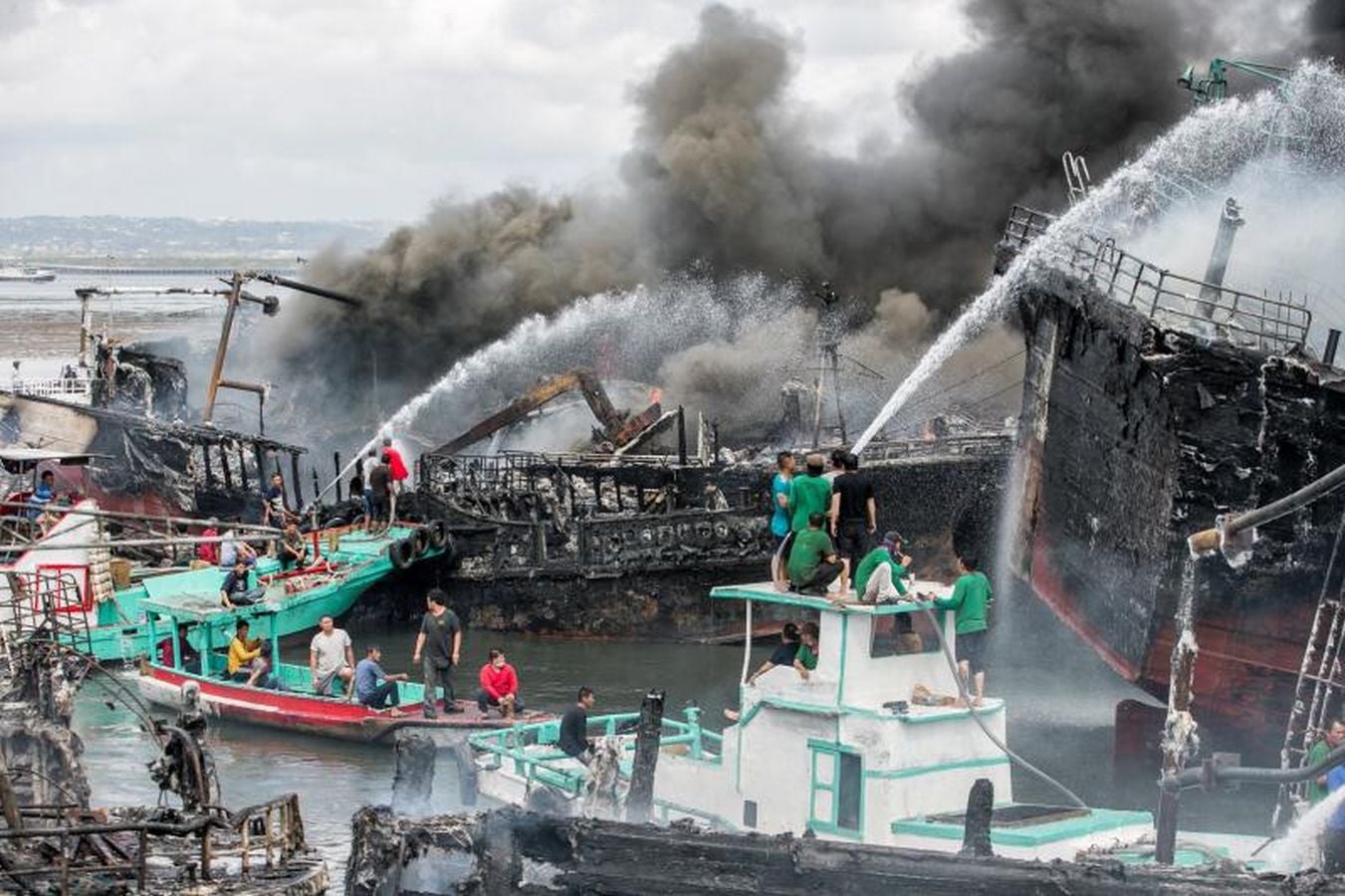 Varios bomberos trabajan en la extinción de un incendio de un barco en el puerto de Benoa, en Bali (Indonesia).