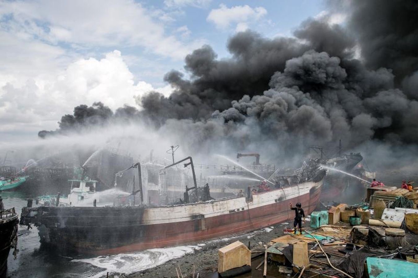 Varios bomberos trabajan en la extinción de un incendio de un barco en el puerto de Benoa, en Bali (Indonesia).