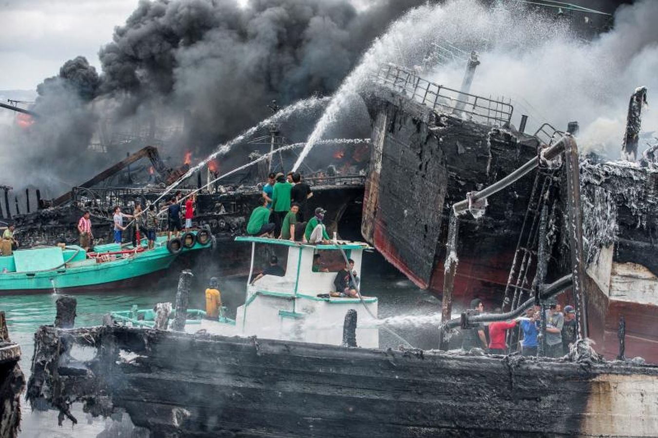 Varios bomberos trabajan en la extinción de un incendio de un barco en el puerto de Benoa, en Bali (Indonesia).