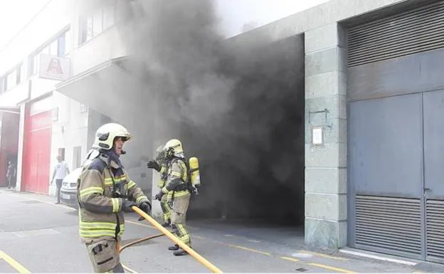 Los bomberos tratan de sofocar el incendio originado en el interior de un garaje
