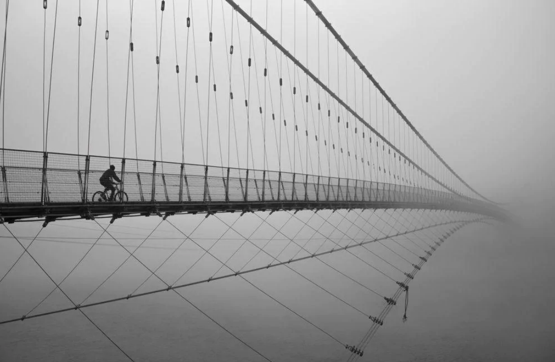 Un transeúnte atraviesa el puente de Ram Jhula en la India. "De repente vi a un hombre en bici que se dirigía hacia el puente. Por suerte, el puente estaba vacío. Encuadré el momento en mi mente y presioné el obturador para capturar la imagen", tomada en el instante perfecto, simulando que puente no tiene fin y creando en nuestras mentes un viaje del ciclista hacia el cielo.