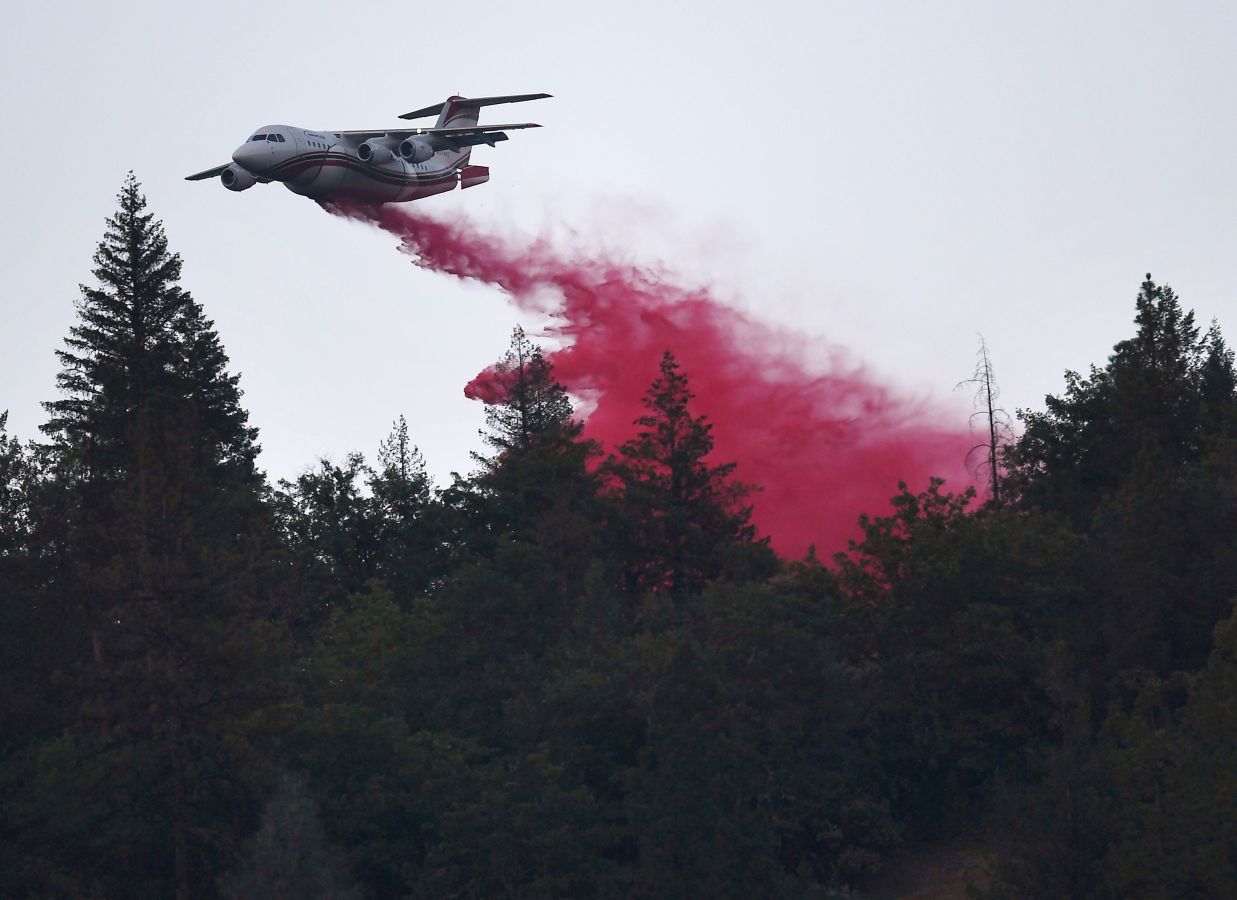 Un avión expulsa retardante rojo para frenar el fuego