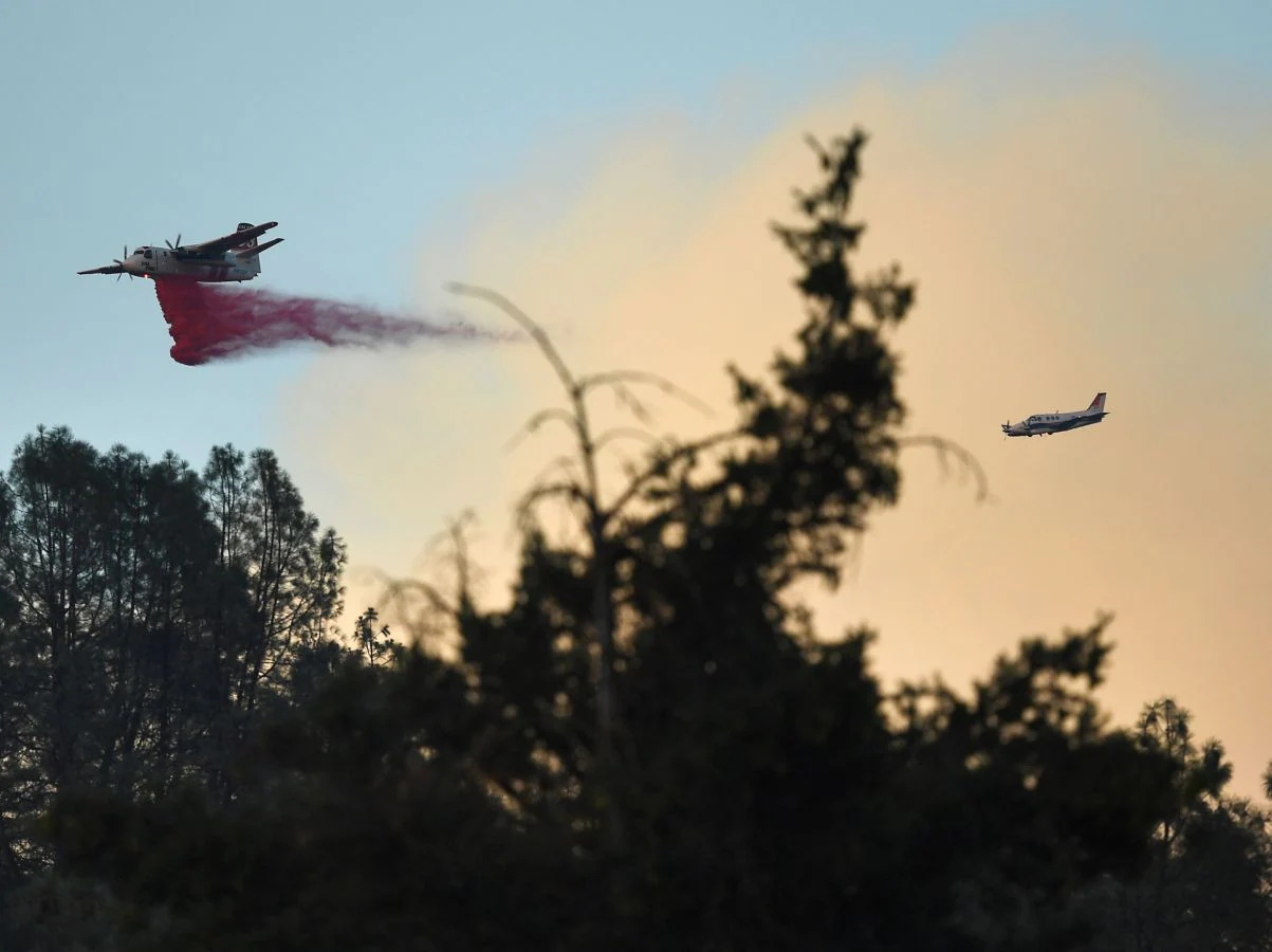 Un avión expulsa retardante rojo para frenar el fuego