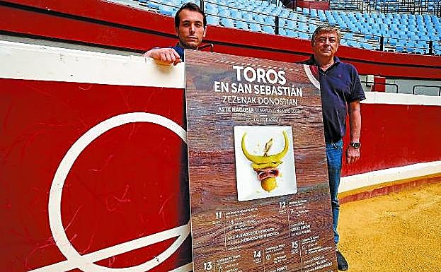 Manuel Martínez Azcárate y Pablo Martínez Labiano posan en el coso de Illunbe junto al cartel de la feria taurina de Semana Grande, que se celebrará desde el sábado 11 al 15 de agosto.