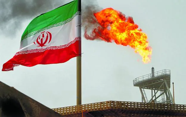 Una bandera iraní ondea ante una llama de gas en una plataforma petrolífera en el Golfo Pérsico.