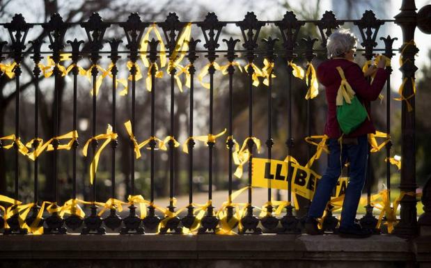 Una mujer coloca lazos amarillos en la verja del Pac de la Ciutadella. 