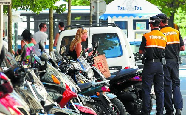 Dos agentes de Movilidad ajenos a la información controlan un aparcamiento de motos. 