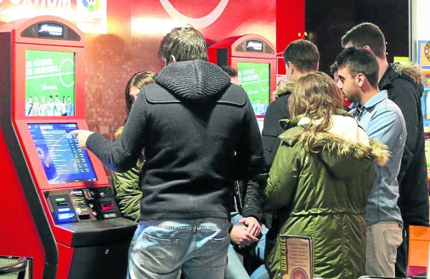 Un grupo de jóvenes observa las apuestas en una máquina de un salón de juegos.