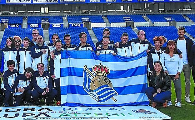 Los jugadores de la Real acompañados de sus padres y Xabi Prieto, entre otros, posan en el césped de Anoeta antes de viajar a Tarragona.