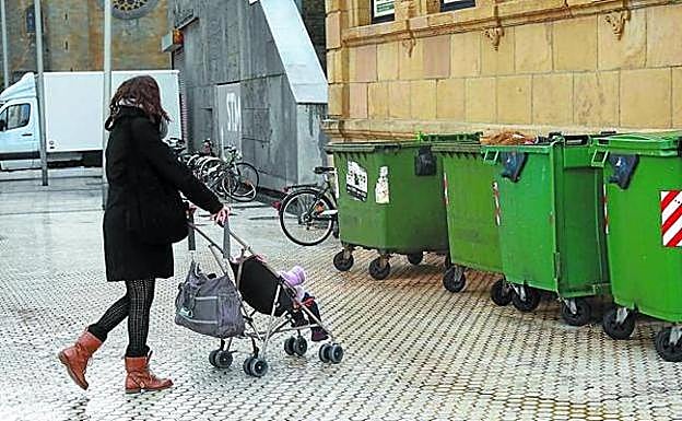 Una mujer con un cochecito se dirige a uno de los contenedores de la calle San Juan donde fue arrojado el bebé. 