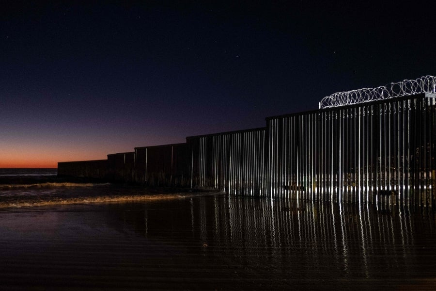 La gente camina cerca de la valla fronteriza entre México y Estados Unidos en Playas de Tijuana, México. El presidente Donald Trump advirtió el miércoles pasado que el gobierno federal de los EE. UU. se mantiene firme en su deseo de reforzar el muro fronterizo con México.