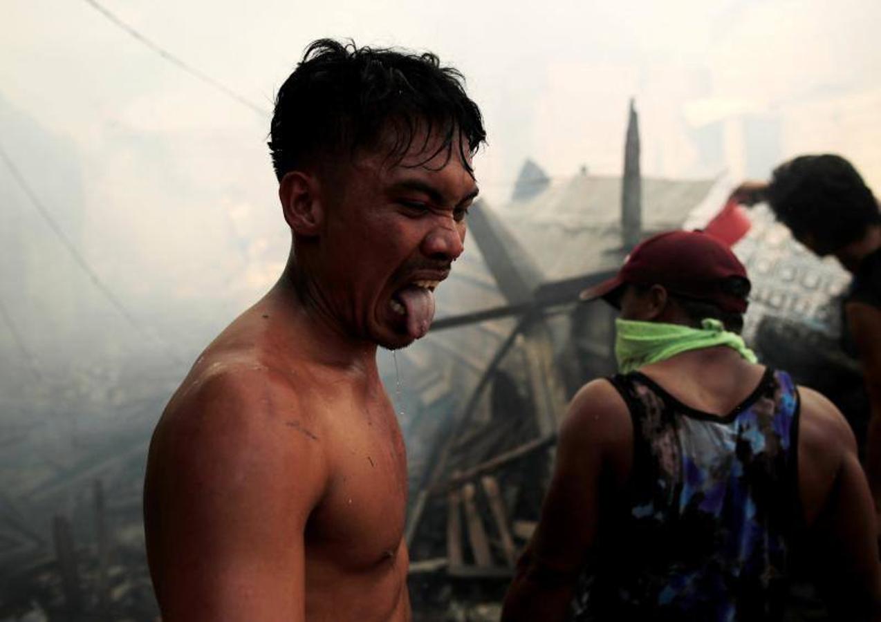 Residentes se afanan por apagar las llamas durante el incendio originado en un barrio de chabolas de Manila, en Filipinas, hoy, 11 de enero de 2019. El incendio destrozó las viviendas de al menos 100 familias pobres.