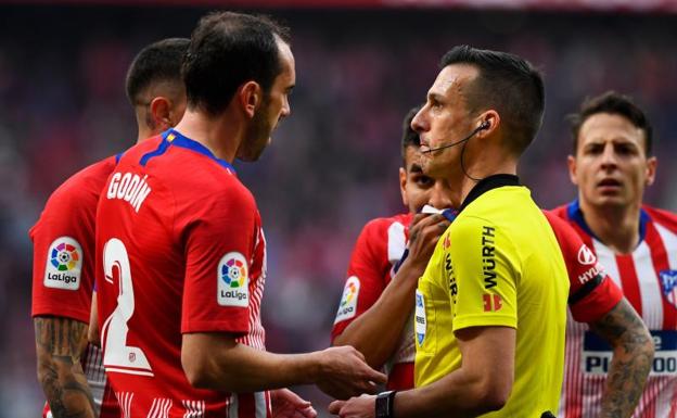 Los jugadores del Atlético hablan con Estrada Fernández tras la acción del penalti a Vinicius.