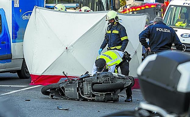 Guardias municipales y bomberos examinan la moto de la víctima.