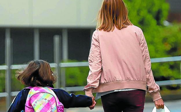 Una niña va al colegio acompañada de su madre.