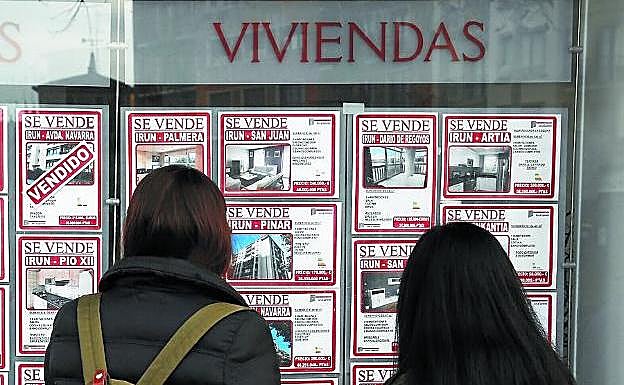 Dos jóvenes observan la oferta de viviendas de una inmobiliaria en Irun.