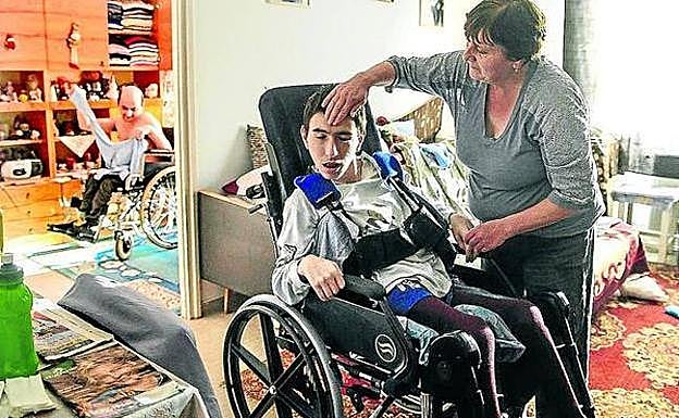 Una mujer atiende a su hijo discapacitado.