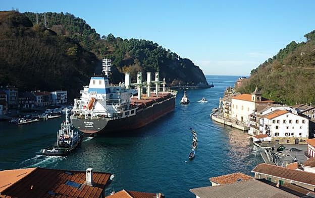 Un carguero sale por la estrecha bocana de Pasaia escoltado por los prácticos del puerto
