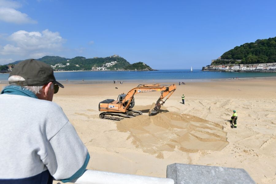 Las excavadoras trabajan ya en las playas donostiarras realizando trabajos de explanación de la arena para poder instalar posteriormente los servicios para el verano (toldos, cafetería, etcétera).