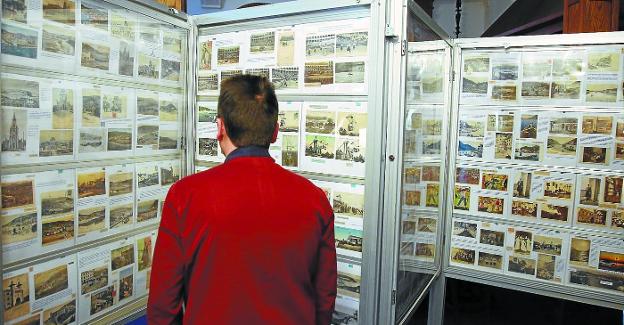Un hombre observa la exposición de más de 2.000 postales del Club Cantábrico.