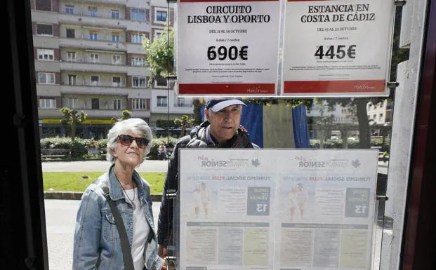 Dos personas observan las ofertas de viajes en una agencia de San Sebastián