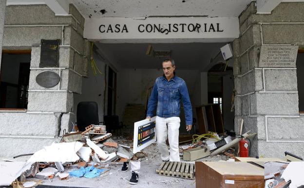 Un hombre saca un cuadro del Ayuntamiento de la localidad orensana de Beade, tras la explosión de un artefacto colocado en la puerta del consistorio, dentro de una olla a presión, en octubre de 2013. 
