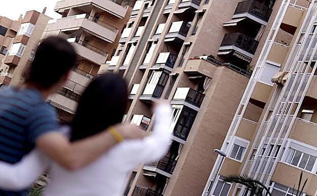 Una pareja joven observa un edificio de viviendas en las que aspiran a residir.