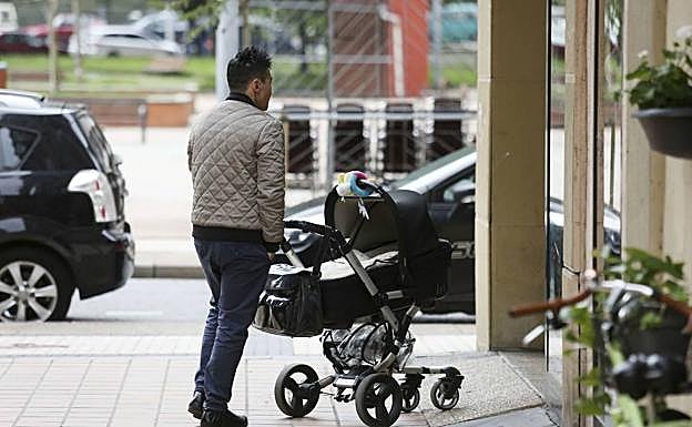 Un hombre pasea un carrito de bebé. 
