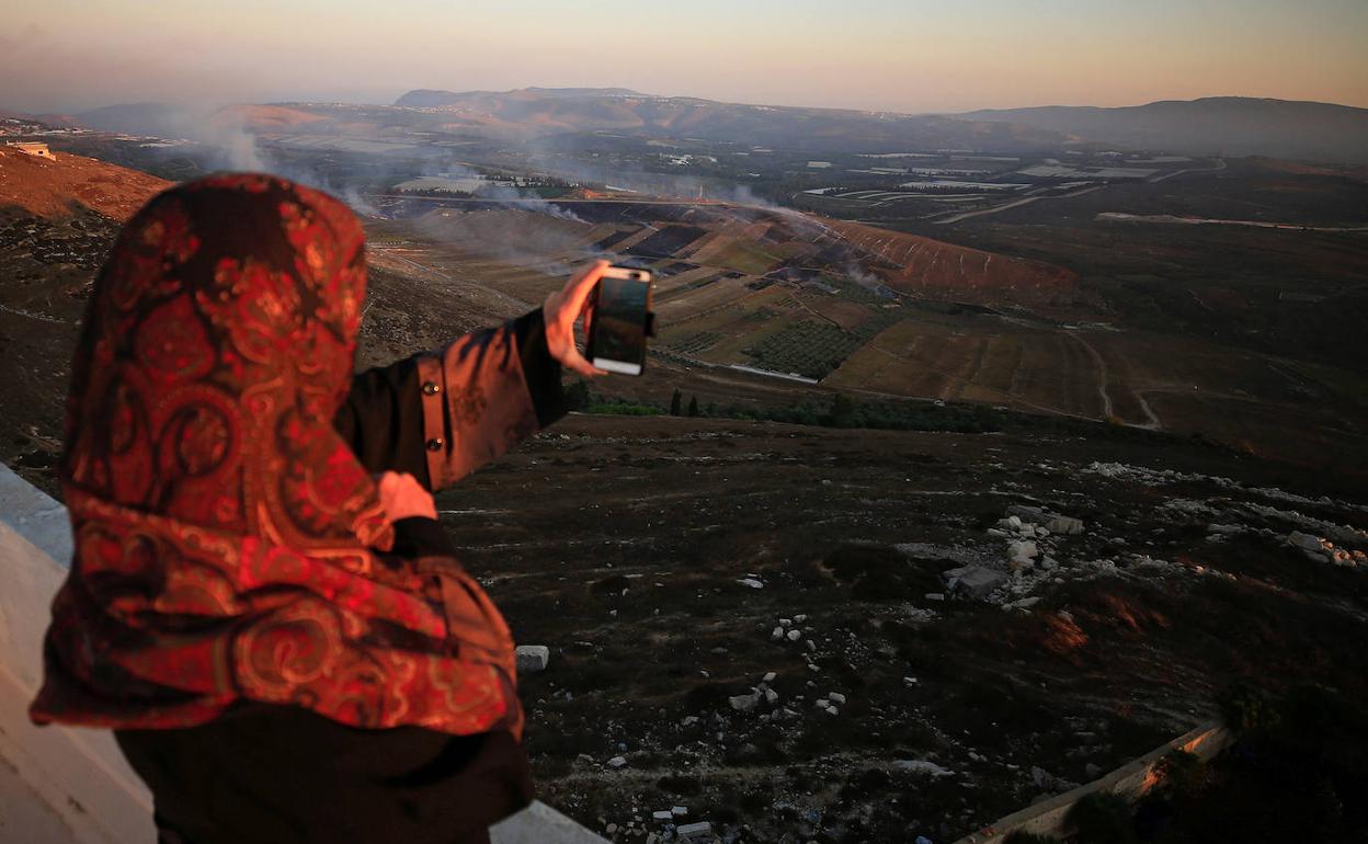 Una mujer graba con su teléfono los efectos provocados por los bombardeos israelíes en la zona fronteriza.