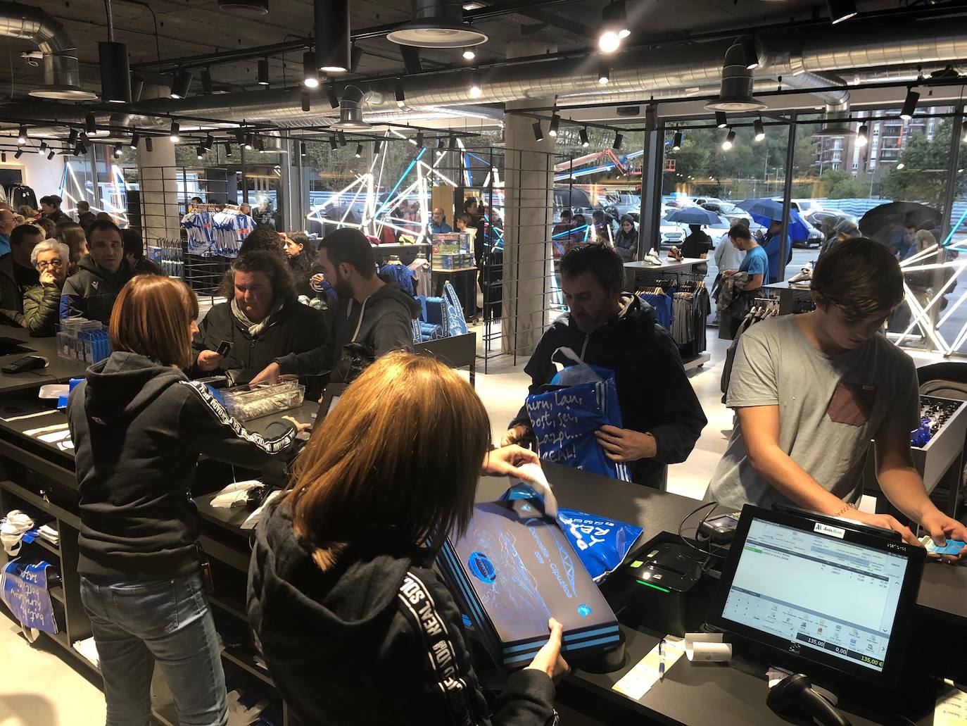 Cientos de aficionados realistas han esperado durante varias horas bajo la lluvia en las tiendas de la Real Sociedad para comprar una elástica