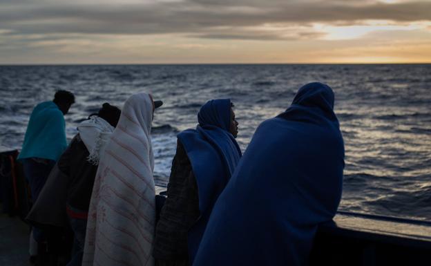 Un grupo de migrantes mira hacia el horizonte.