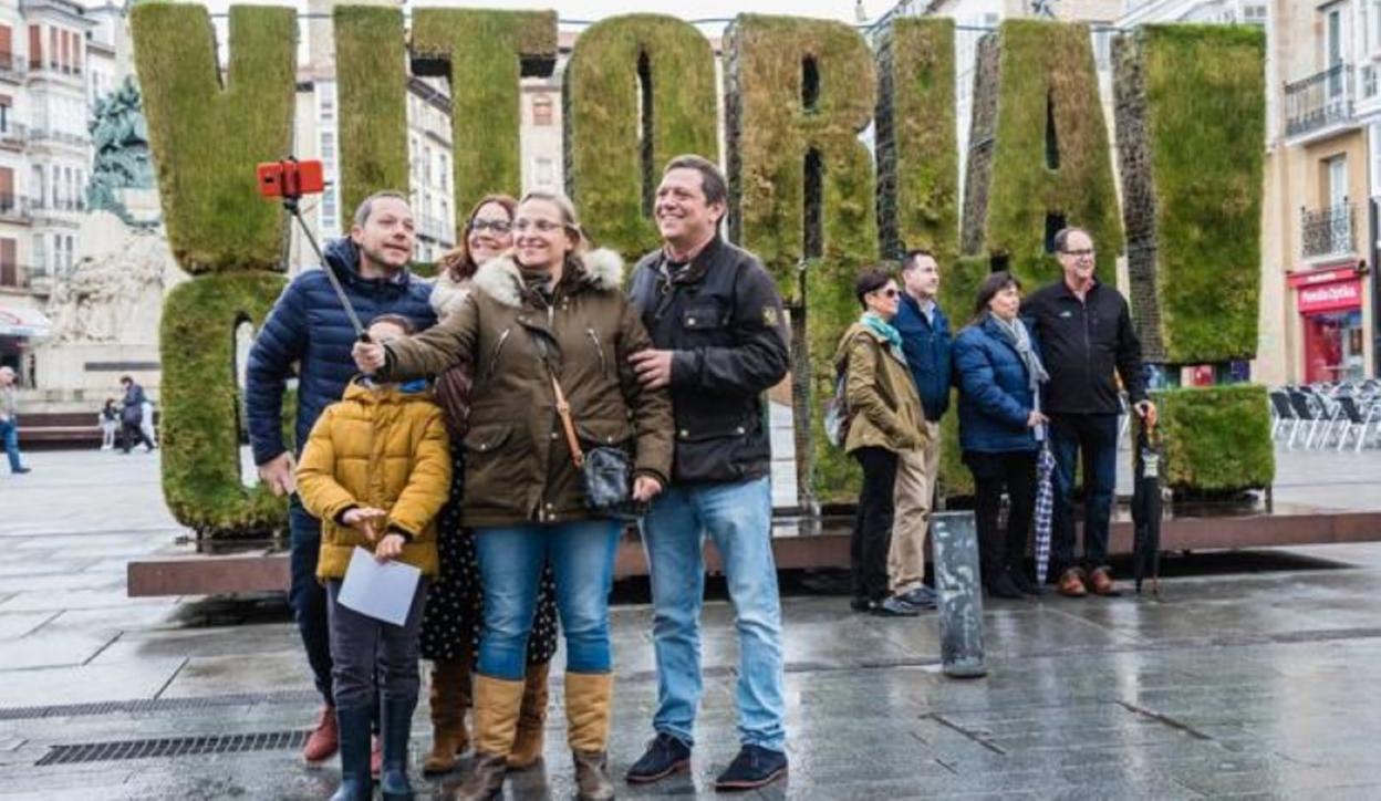 Un grupo de turistas se fotografía junto a la escultura vegetal de la plaza de la Virgen Blanca.