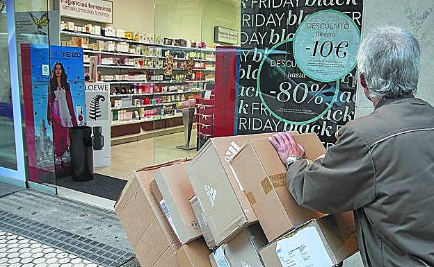 Un repartidor accede cargado de paquetes a una tienda del centro de San Sebastián con ofertas para el 'Black Friday'.