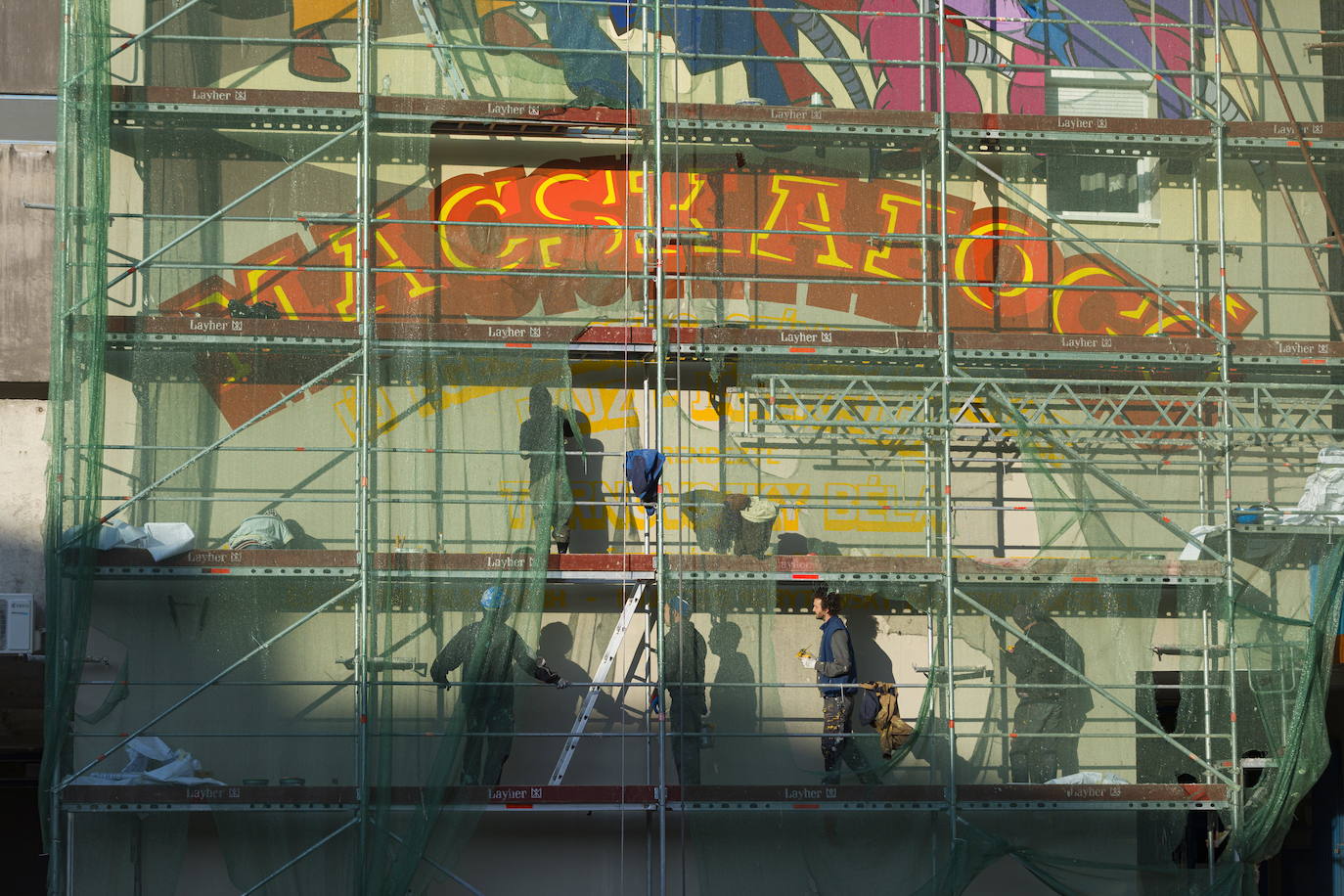 Los miembros del grupo Szines Varos (ciudad colorida) trabajan en un andamio para crear un mural en un edificio residencial en el Distrito VIII de Budapest. La obra de arte de 600 metros cuadrados representa a los personajes principales de la popular caricatura húngara Macskafogo (lit. Cat Catcher) de 1986, que se distribuyó como 'cat city' en Estados Unidos. El colectivo artístico ha realizado muchos murales a gran escala en Budapest y otras ciudades húngaras, así como en Moscú, Berlín y Londres, desde su fundación en 2008.
