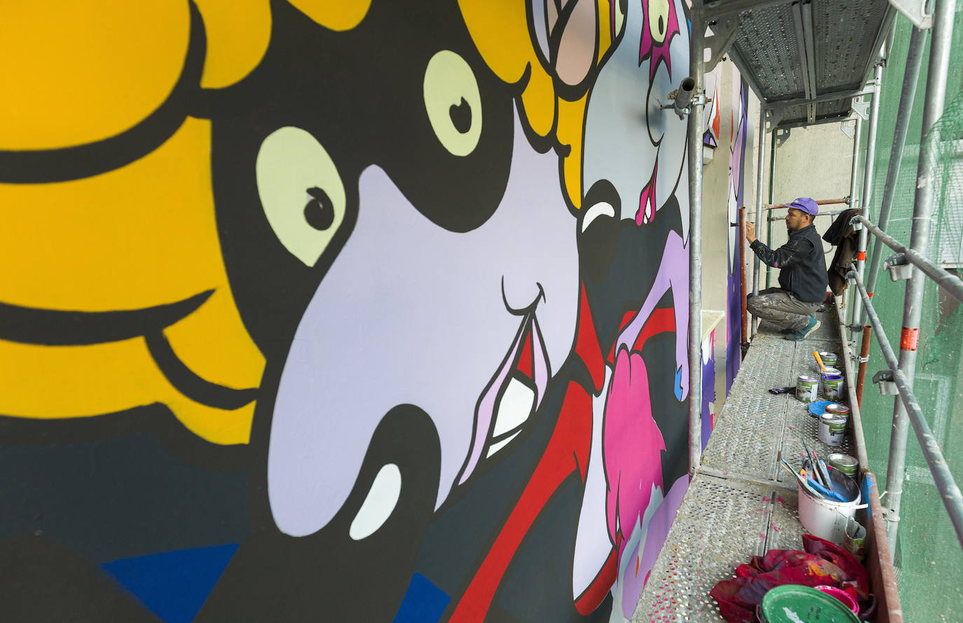 Los miembros del grupo Szines Varos (ciudad colorida) trabajan en un andamio para crear un mural en un edificio residencial en el Distrito VIII de Budapest. La obra de arte de 600 metros cuadrados representa a los personajes principales de la popular caricatura húngara Macskafogo (lit. Cat Catcher) de 1986, que se distribuyó como 'cat city' en Estados Unidos. El colectivo artístico ha realizado muchos murales a gran escala en Budapest y otras ciudades húngaras, así como en Moscú, Berlín y Londres, desde su fundación en 2008.