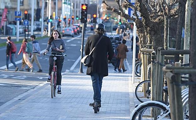 Un usuario circula con su patinete eléctrico por Donostia con auriculares, acción prohibida expresamente en la ordenanza.