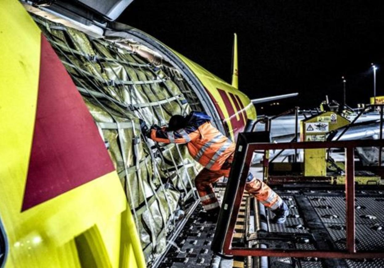 Un trabajador introduce mercancías en un avión. 